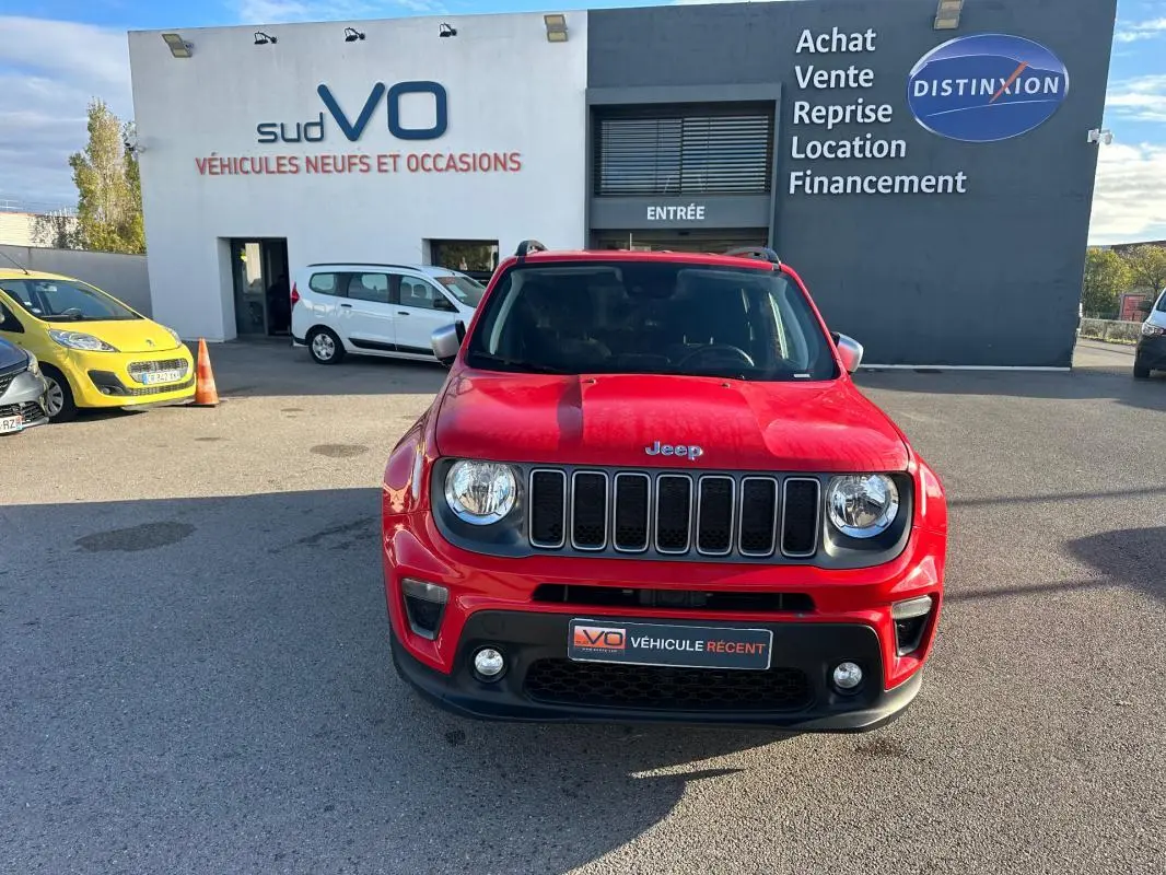 Vue de face d'un Jeep Renegade rouge 2022 avec calandre à sept fentes et phares ronds, stationné devant un concessionnaire.