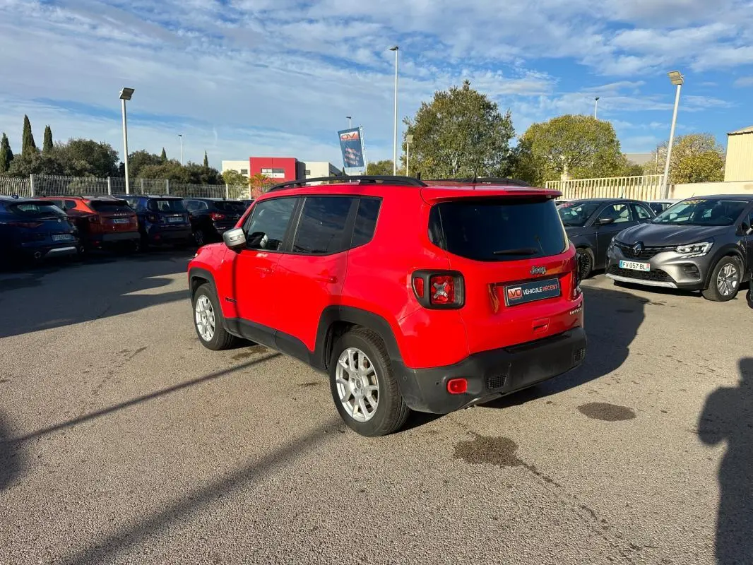 Jeep Renegade rouge vue 3/4 arrière droit avec barres de toit et jantes alliage 17 pouces sur parking.