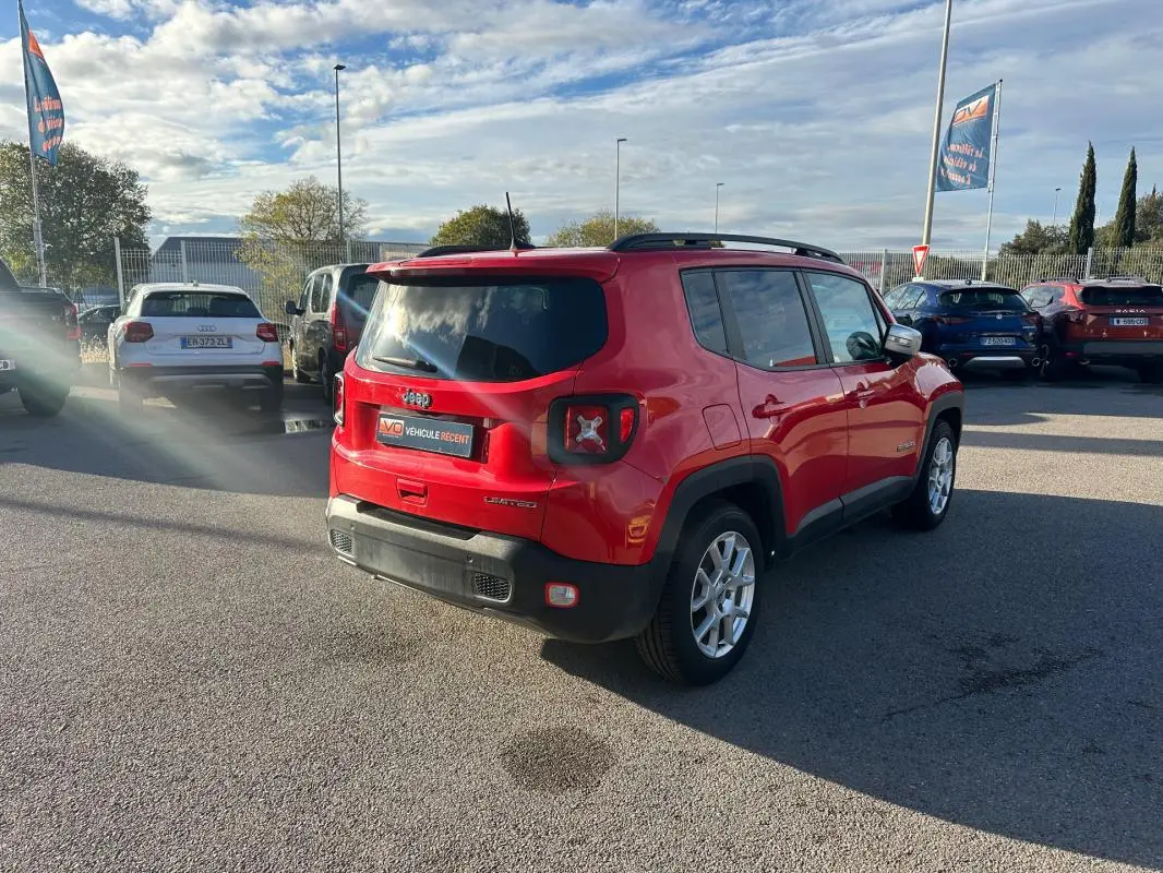Jeep Renegade rouge vue 3/4 arrière droit, avec barres de toit et jantes alliage 17 pouces sur parking.