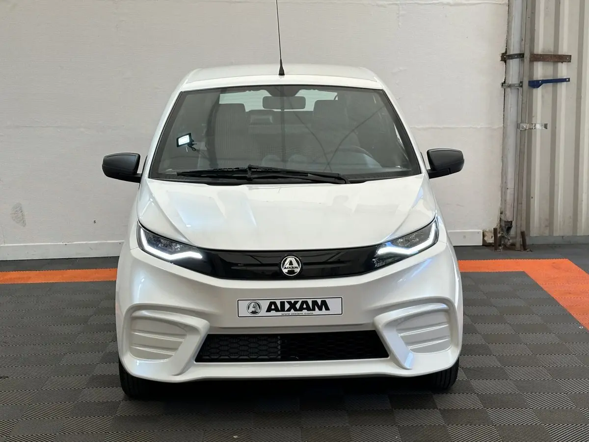 Vue frontale d'une Aixam Ambition E City Pack blanche 2025 avec phares LED et rétroviseurs noirs côté conducteur équipé caméra.