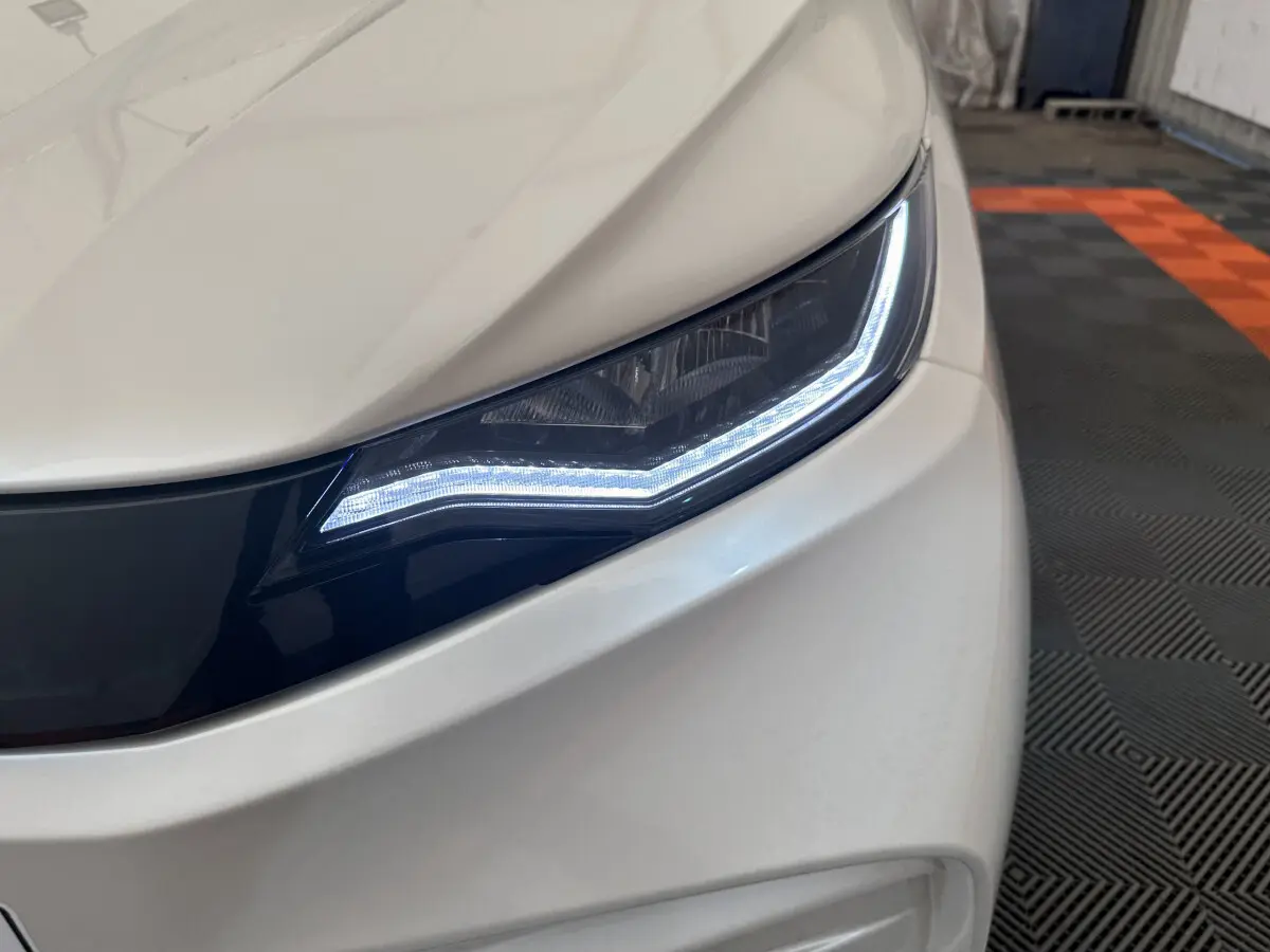 Gros plan sur le phare avant droit blanc de l'AIXAM AMBITION E CITY PACK 2025 avec éclairage LED distinctif.