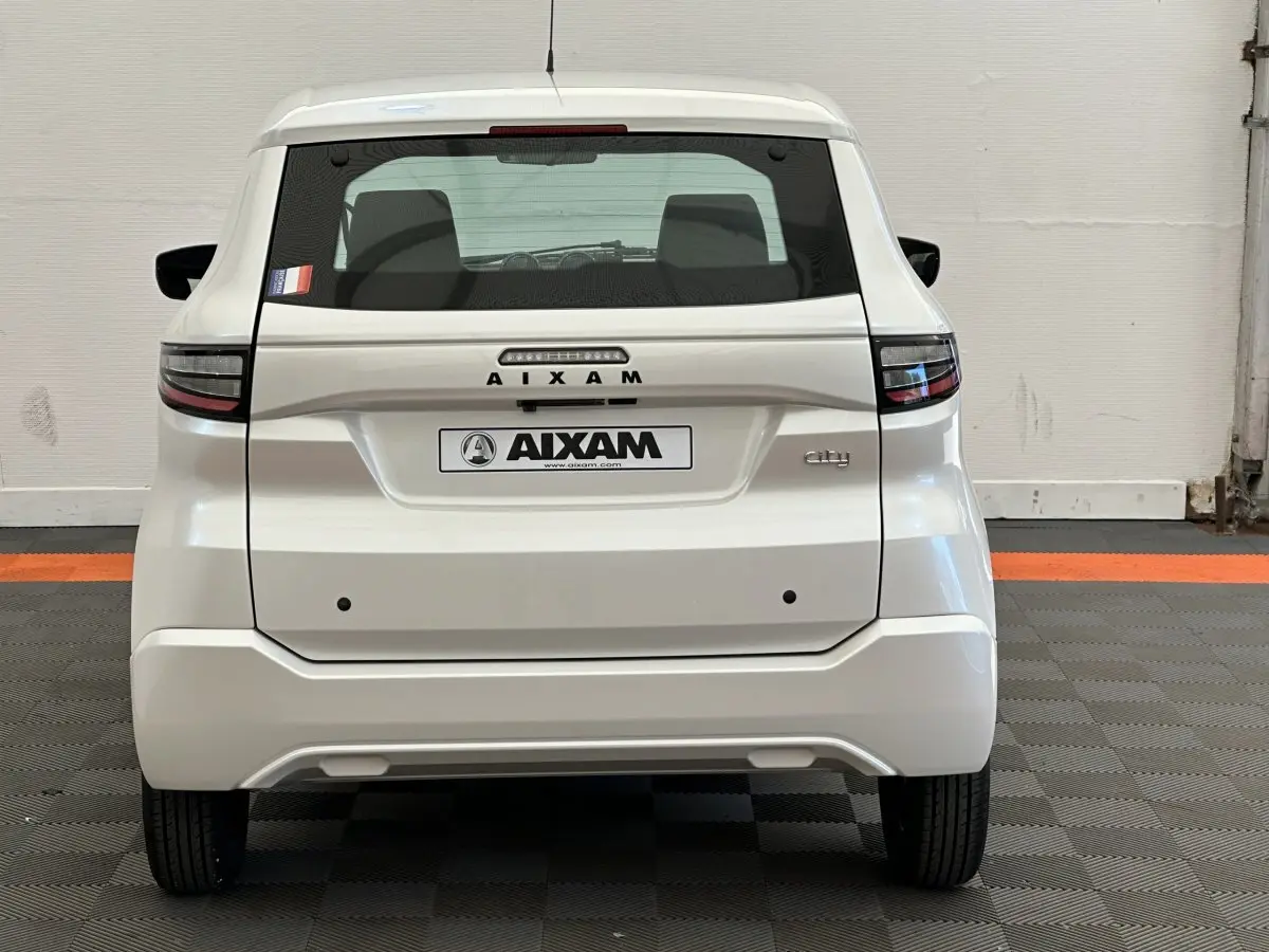 Vue arrière d'une Aixam Ambition E City Pack blanche 2025 avec feux LED et logo distinctif sur fond neutre.