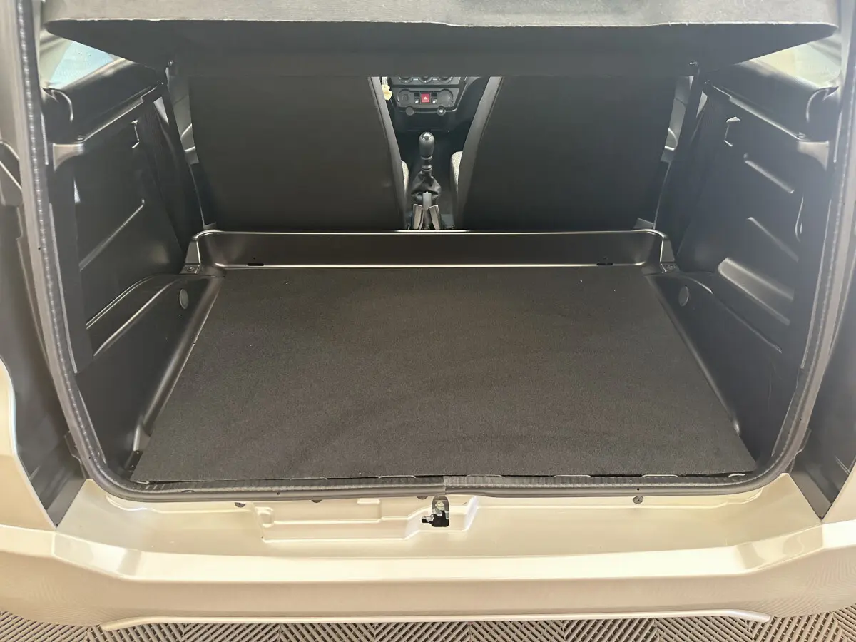 Coffre ouvert vu de l'arrière d'une Aixam Ambition E City Pack 2025 blanche, montrant l'espace de chargement vide.