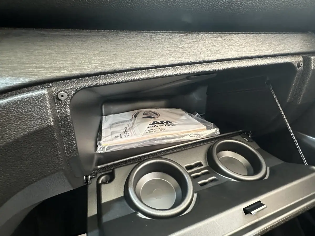 Intérieur de la boîte à gants ouverte de l'AIXAM AMBITION E CITY PACK 2025 avec documentation visible.