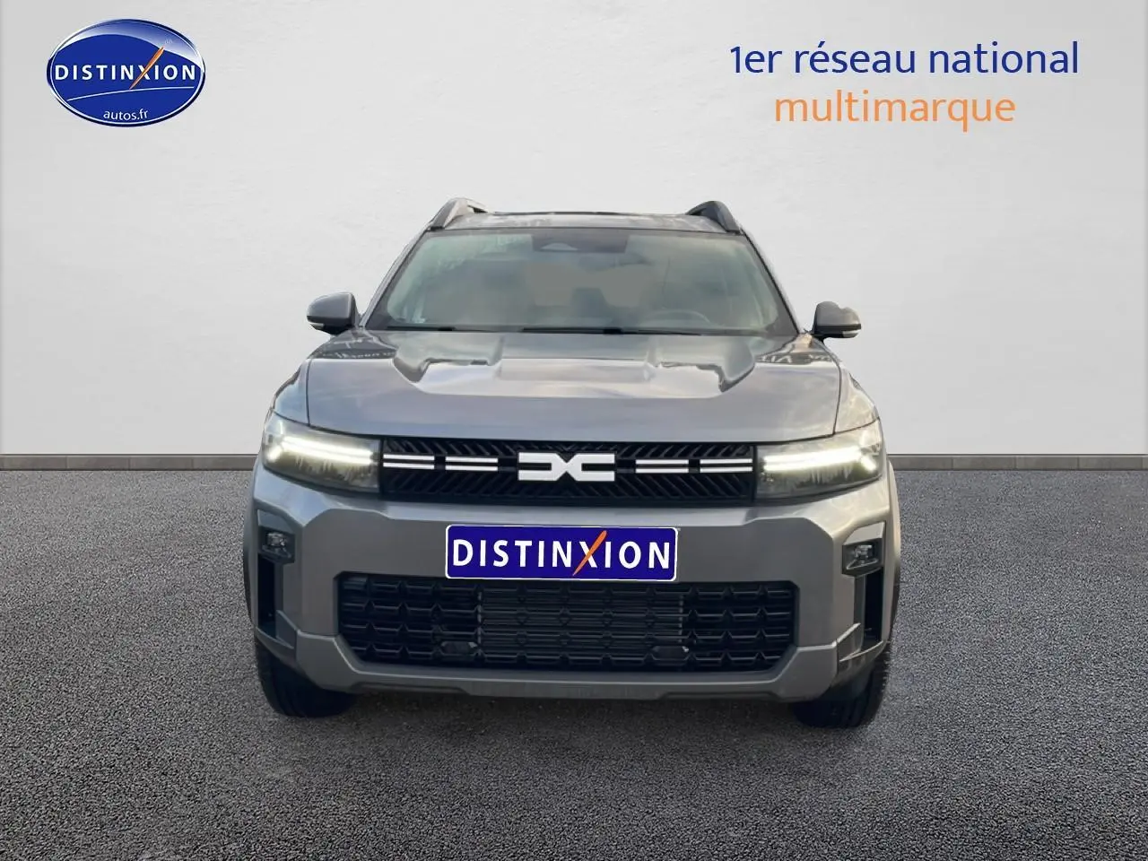 Vue frontale du Dacia Bigster gris schiste 2025 avec calandre noire et phares LED allumés.