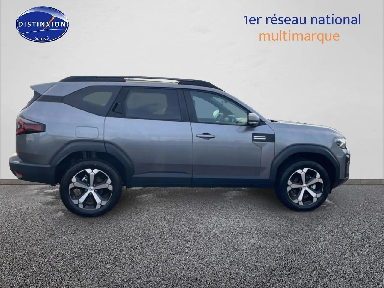 Vue latérale droite du Dacia Bigster gris schiste 2025 avec jantes alliage diamantées et barres de toit noires.