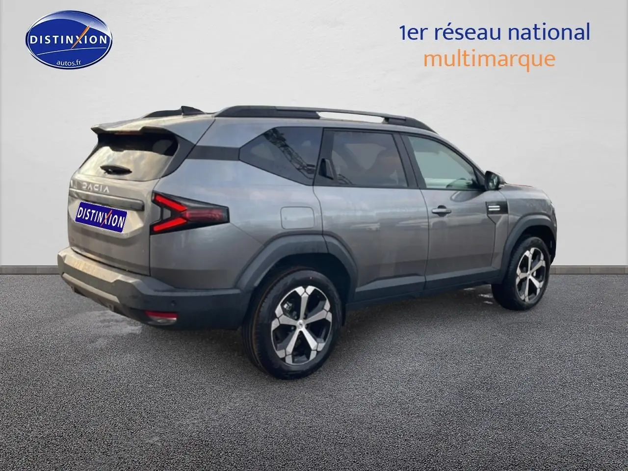 Vue 3/4 arrière droite du SUV Dacia Bigster gris schiste avec jantes alliage diamantées et barres de toit.