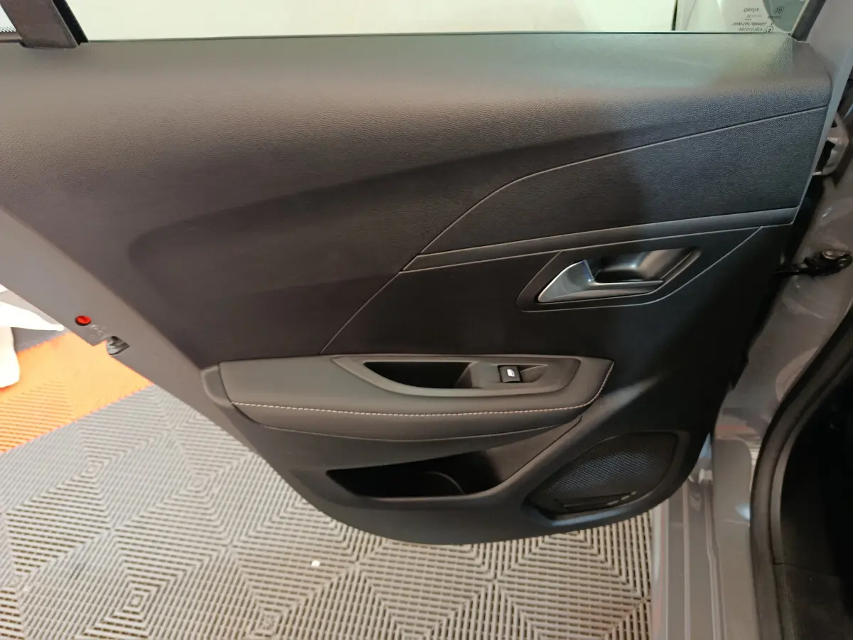Vue rapprochée de la porte arrière droite gris foncé de la Peugeot 208 PureTech 100 S&S Allure avec commande de vitre et haut-parleur intégré.