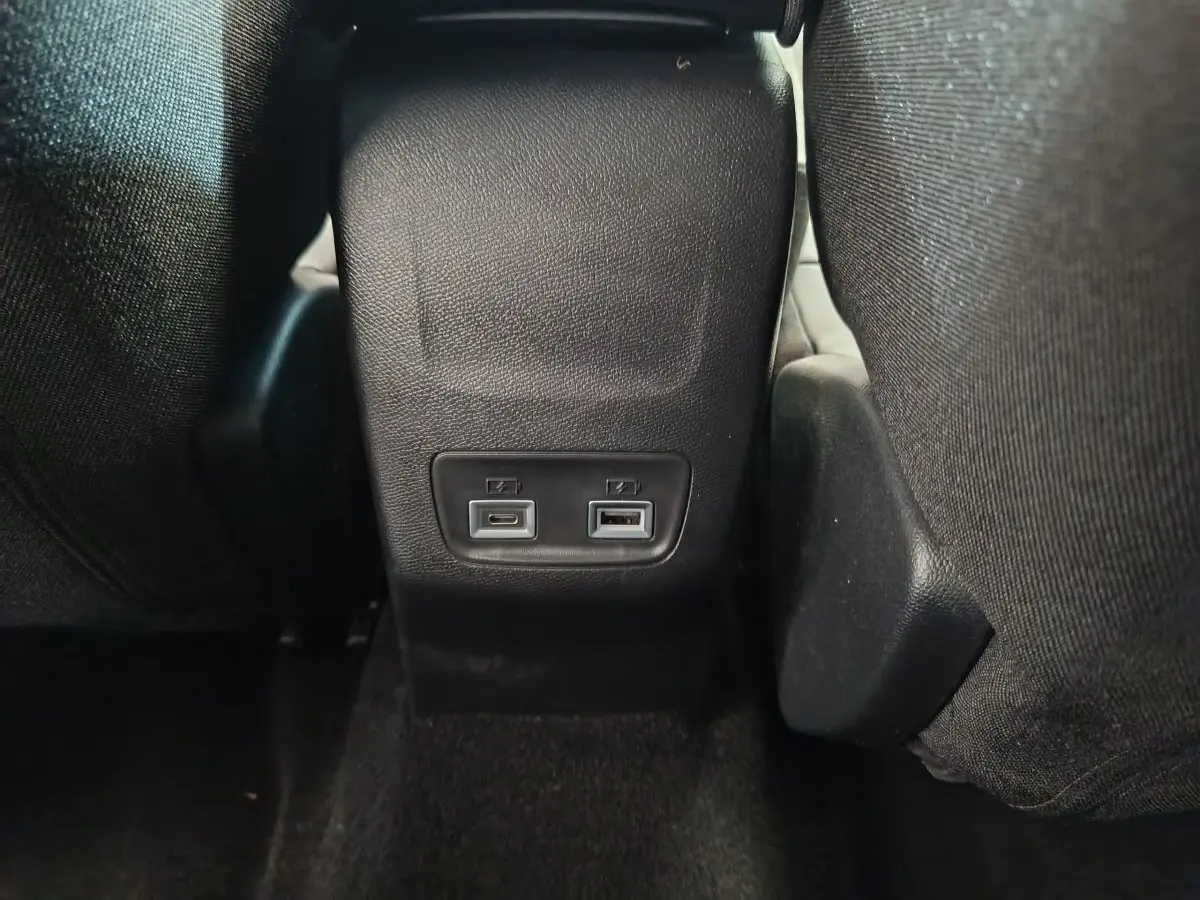 Prise USB type A et USB type C arrière sur console centrale noire du Peugeot 208 gris foncé, vue de dos des sièges.