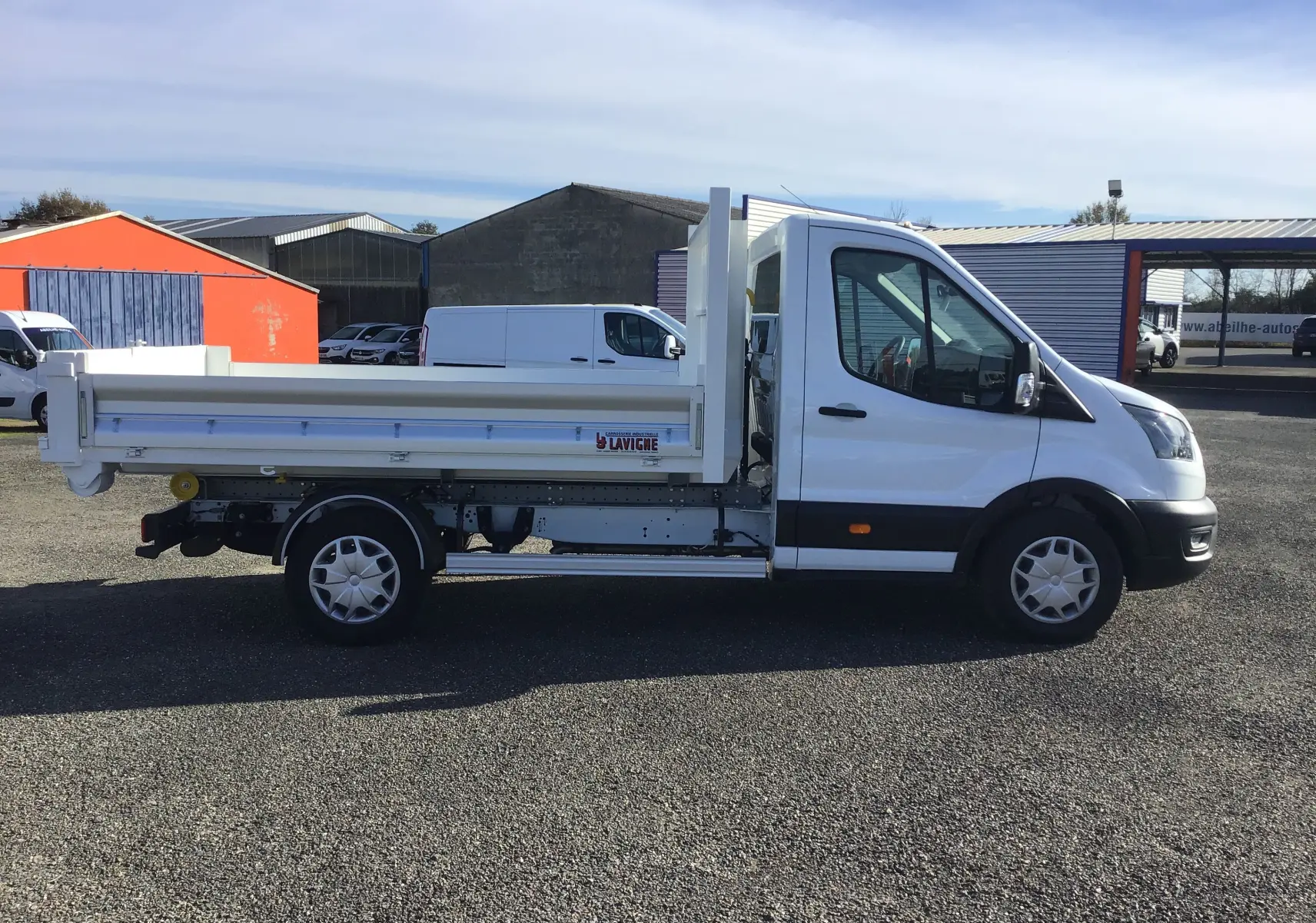 Vue latérale droite d’un Ford Transit Chassis Cabine blanc avec benne basculante et deux portes battantes arrière.