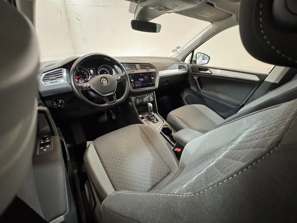 Vue intérieure côté conducteur du Volkswagen Tiguan 2020, montrant le volant cuir, tableau de bord numérique et sièges gris.