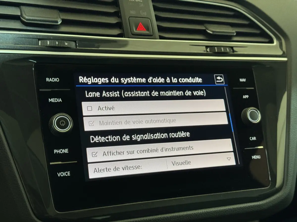 Écran tactile central noir du Volkswagen Tiguan blanc 2020 affichant les réglages d'aide à la conduite.