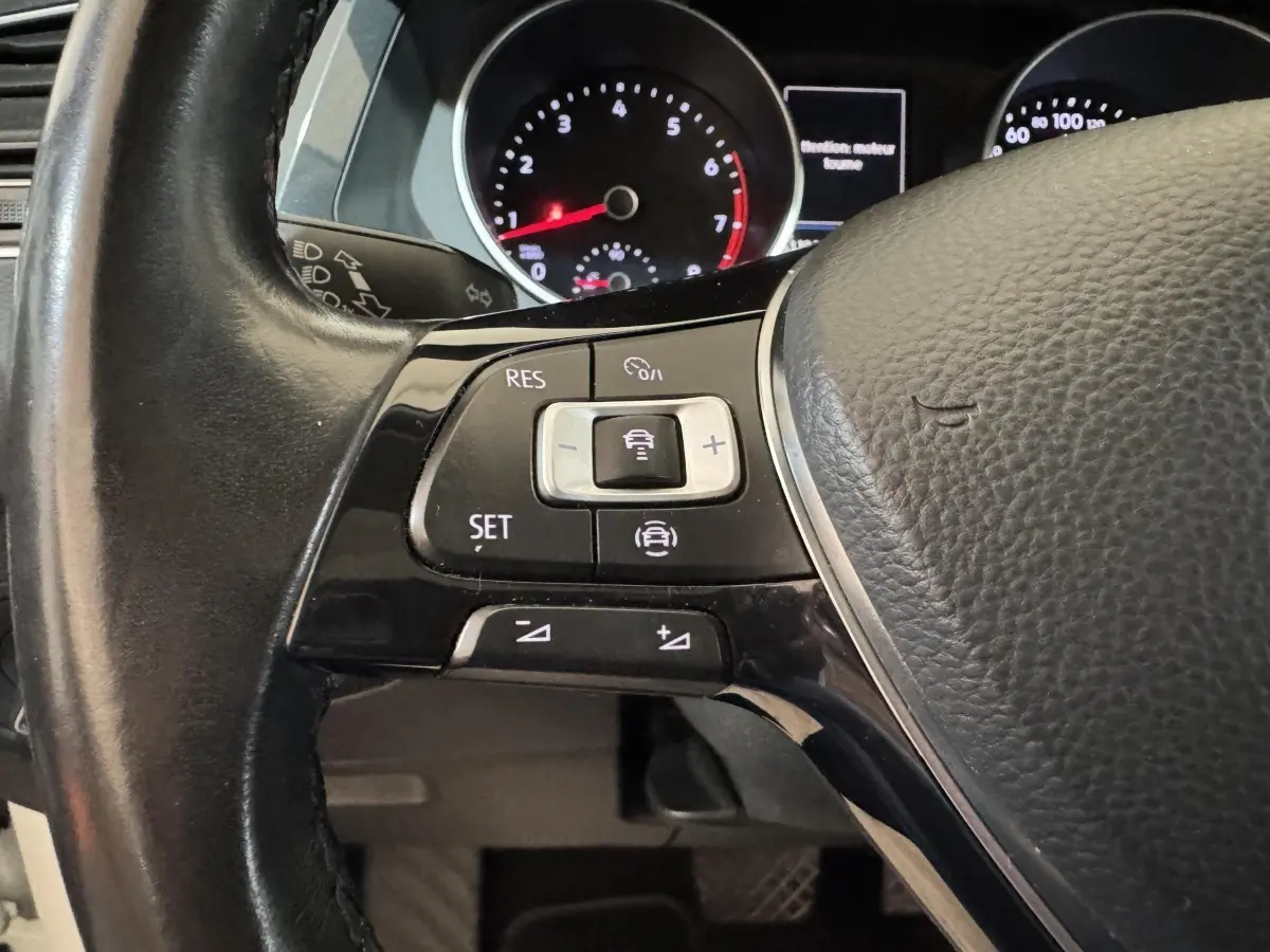 Gros plan sur les commandes du volant cuir noir du Volkswagen Tiguan 2020, avec tableau de bord numérique en arrière-plan.