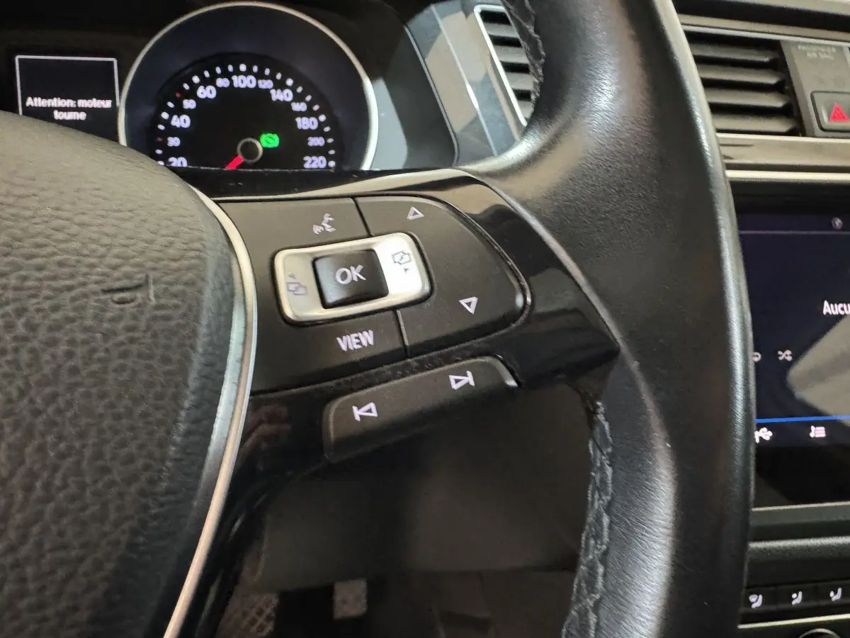 Gros plan sur le volant cuir noir du Volkswagen Tiguan 1.5 TSI 2020 avec commandes multifonctions et tableau de bord visible.