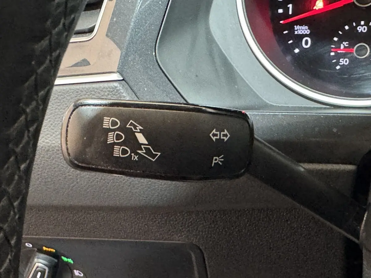 Gros plan sur la commande de clignotants et feux à gauche du volant du Volkswagen Tiguan blanc 2020.