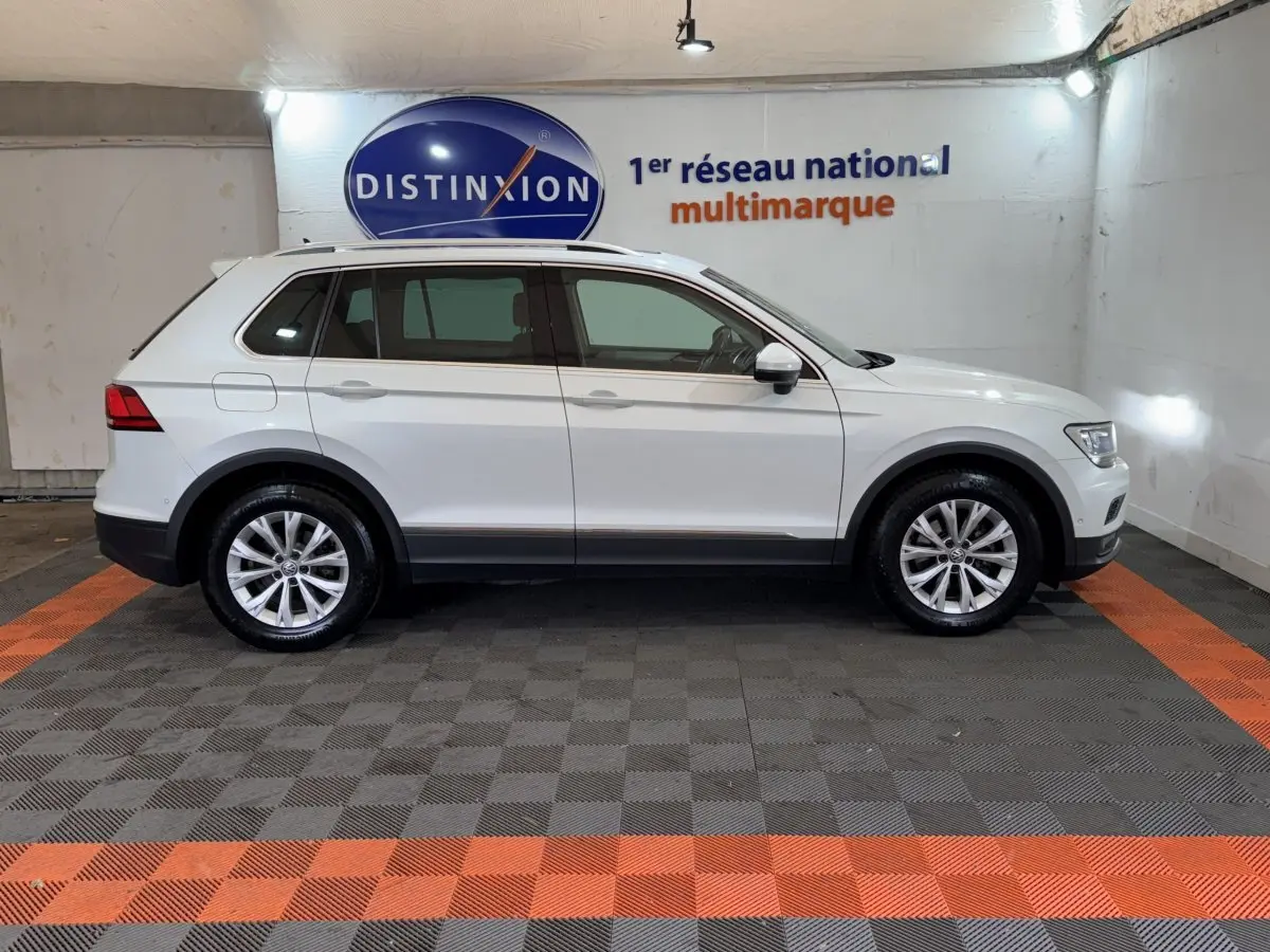 Profil côté gauche d'un Volkswagen Tiguan blanc 2020 garé en intérieur sur sol à damiers gris et orange.