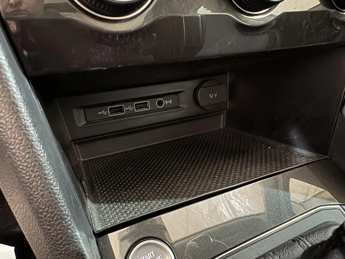 Gros plan sur la console centrale noire du Volkswagen Tiguan 2020 montrant ports USB et prise 12V.