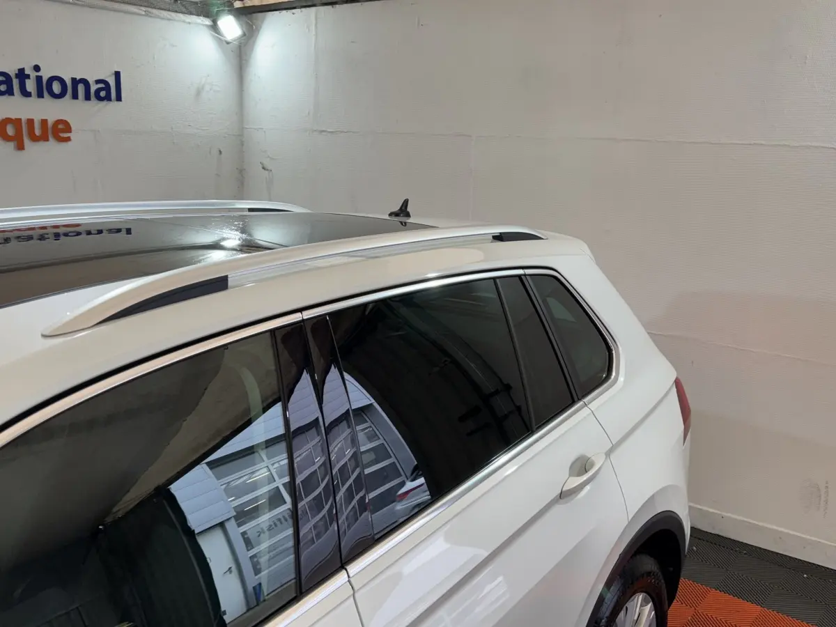 Vue côté droit arrière du Volkswagen Tiguan blanc 2020 avec barres de toit et vitres teintées.