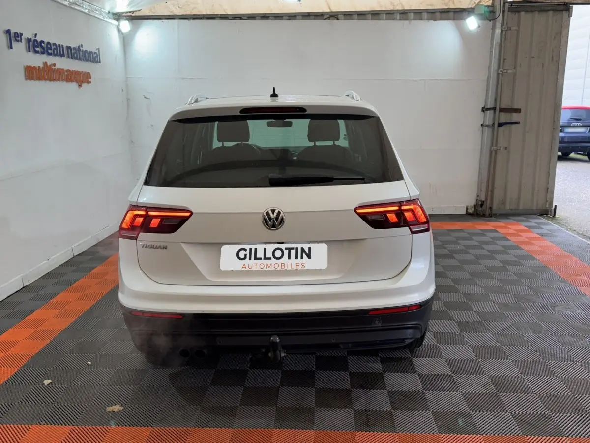 Vue arrière d'un Volkswagen Tiguan blanc 2020 avec feux allumés et attelage dans un garage.