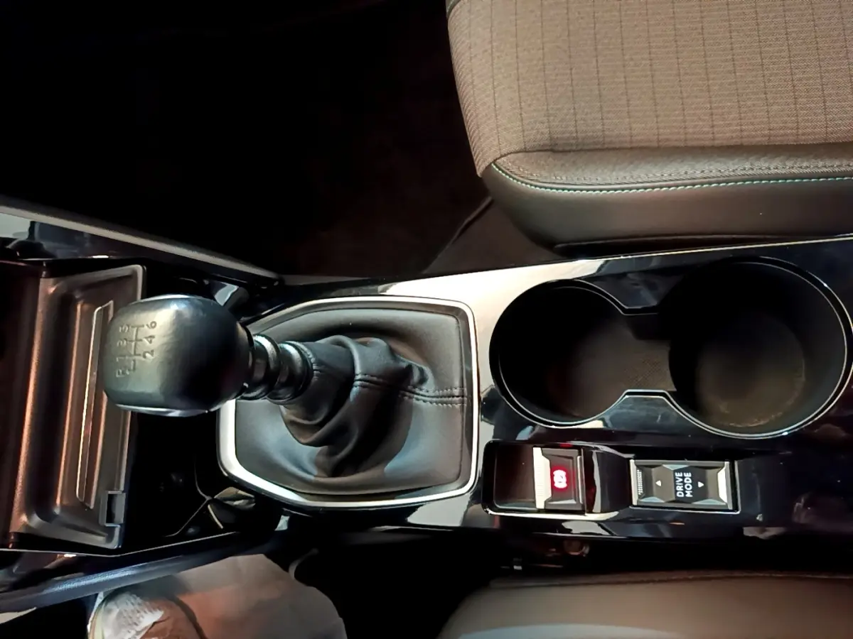 Gros plan sur la console centrale noire de la Peugeot 208 jaune, avec levier de vitesse manuel et porte-gobelets.