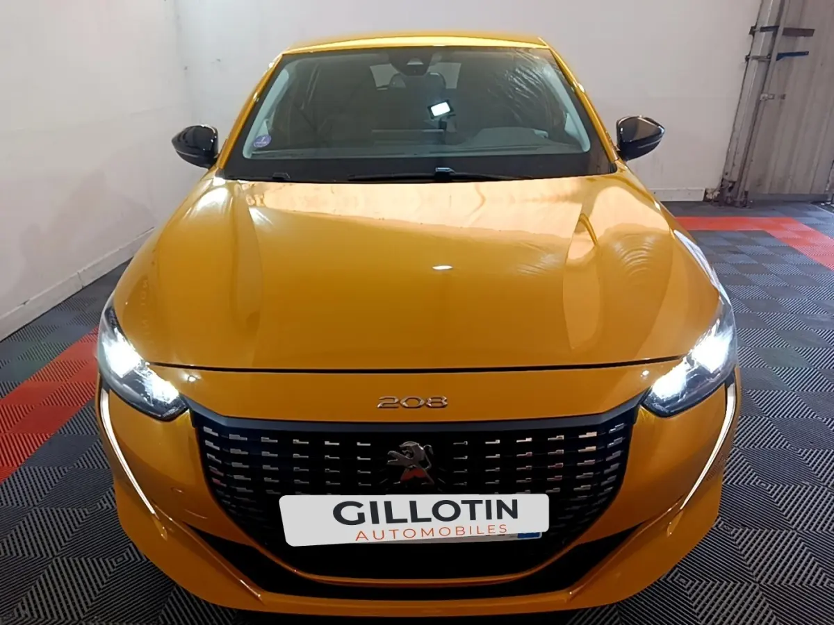 Vue avant frontale d'une Peugeot 208 jaune avec phares LED allumés et calandre noire distinctive.