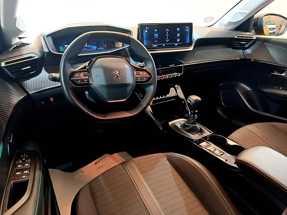 Vue intérieure avant droite du Peugeot 208 PureTech 100 S&S Allure Pack 2023, volant cuir multifonctions et écran tactile central.
