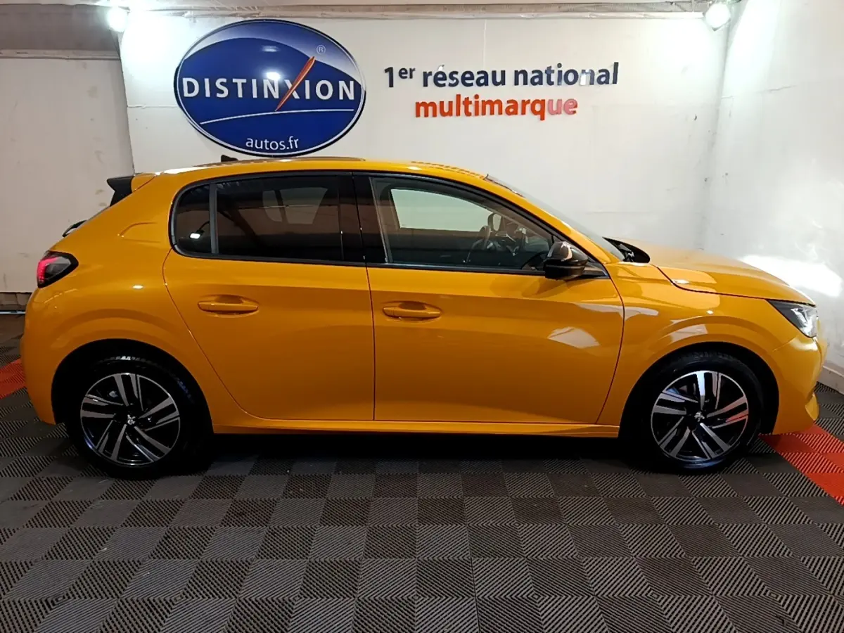 Profil droit d'une Peugeot 208 jaune 2023 dans un showroom avec jantes alliage et vitres teintées.