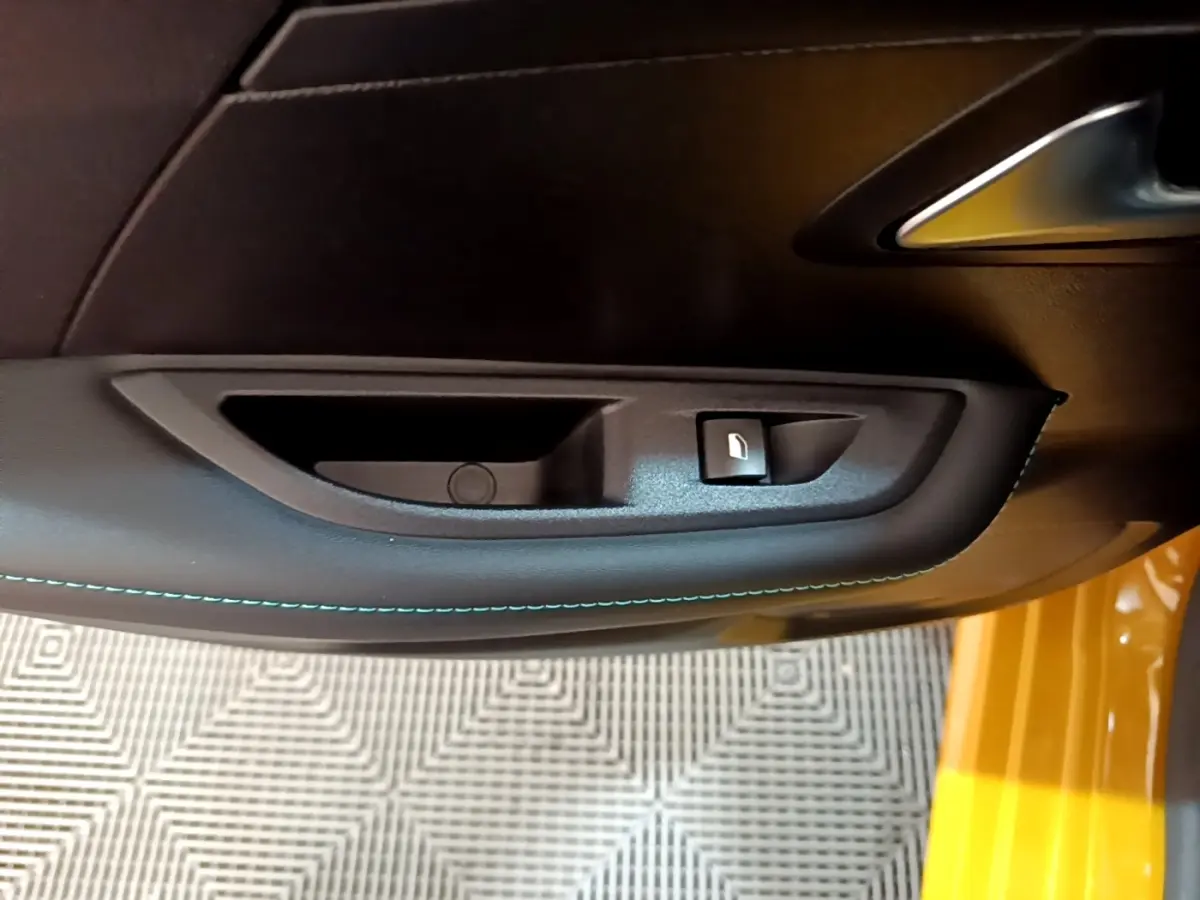 Gros plan sur la poignée intérieure et bouton de verrouillage de la porte côté conducteur d'une Peugeot 208 jaune.