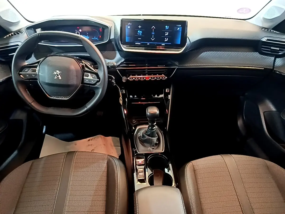 Vue intérieure avant de la Peugeot 208 PureTech 100 S&S Allure Pack 2023, volant cuir multifonctions et écran tactile central.
