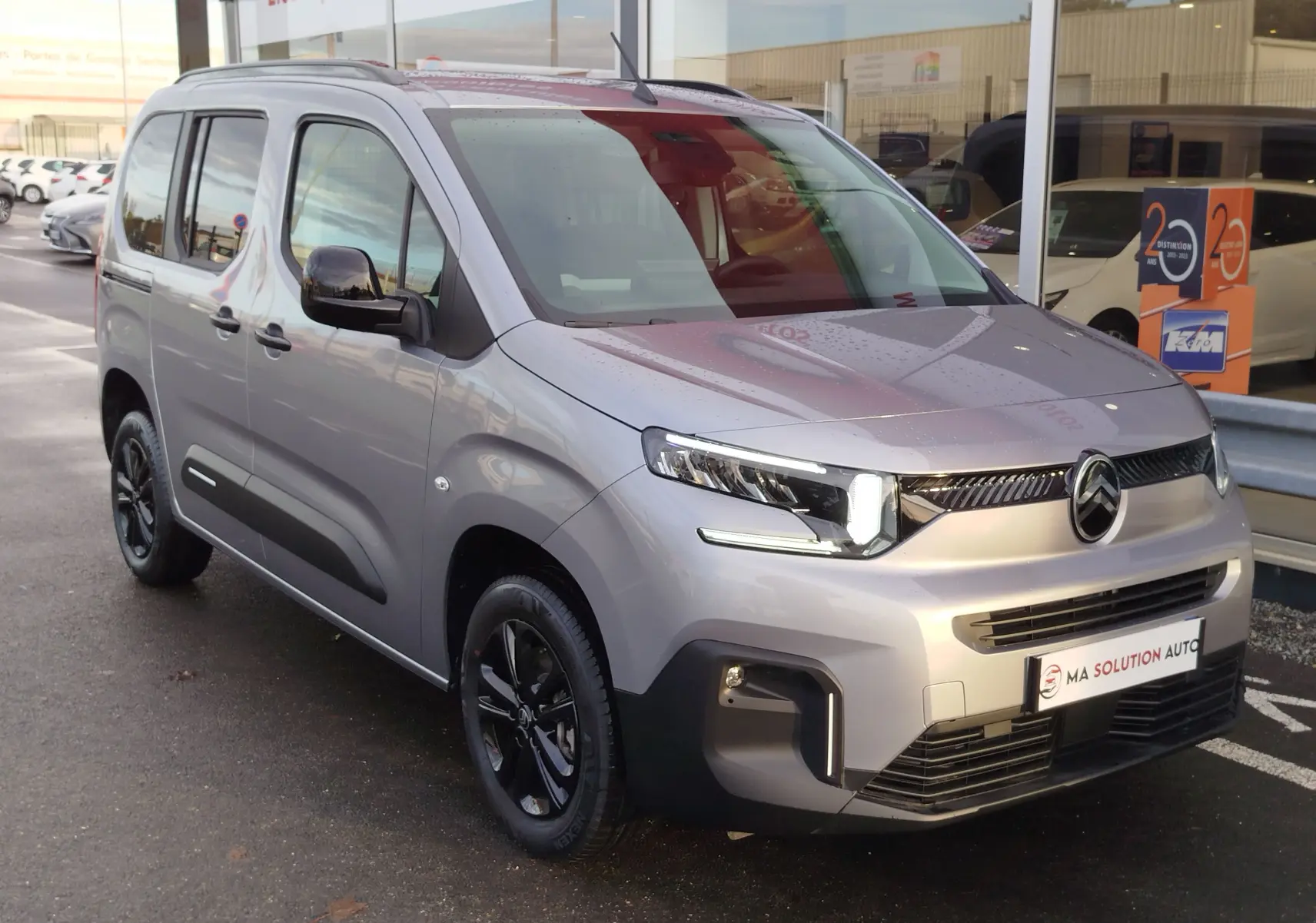 Vue 3/4 avant droit du Citroën Berlingo gris acier 2025 avec phares LED et jantes noires brillantes.