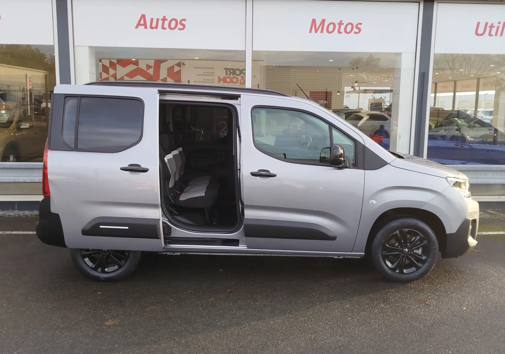 Vue de profil droit d'un Citroën Berlingo gris acier 2025 avec porte coulissante ouverte et jantes noires.