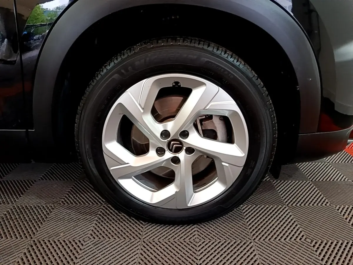 Gros plan sur la roue avant droite d’un Citroën C5 Aircross noir, avec jante alliage argentée à cinq branches.