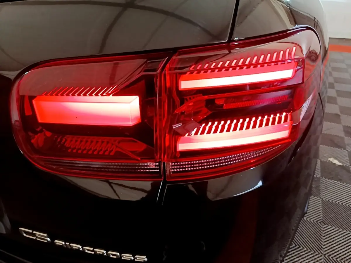 Gros plan sur le feu arrière droit rouge d’un Citroën C5 Aircross noir, avec logo visible sur la carrosserie.