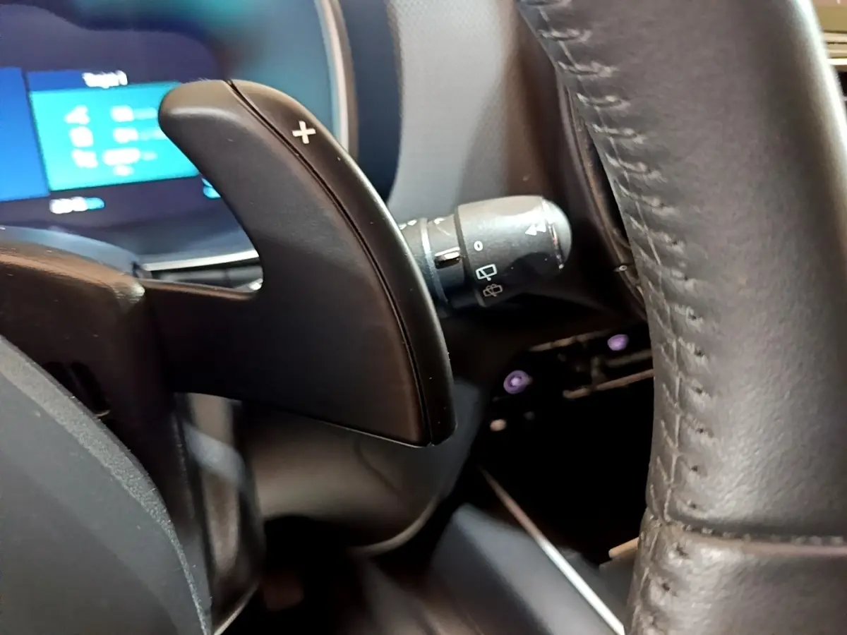 Gros plan sur la palette de changement de vitesses droite en plastique noir et volant cuir du Citroën C5 Aircross hybride 2022.