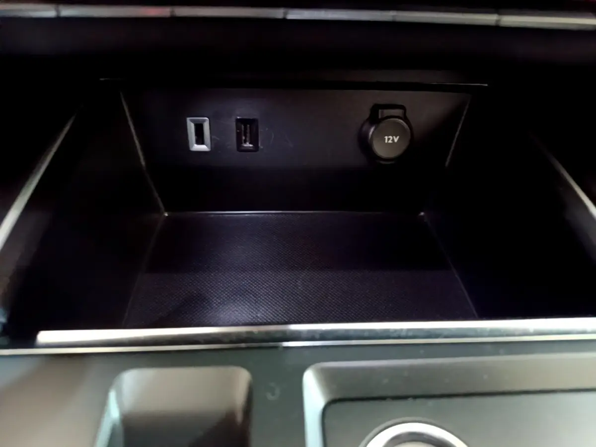 Gros plan sur la prise 12V et ports USB dans le rangement central noir du Citroën C5 Aircross hybride rechargeable 2022.