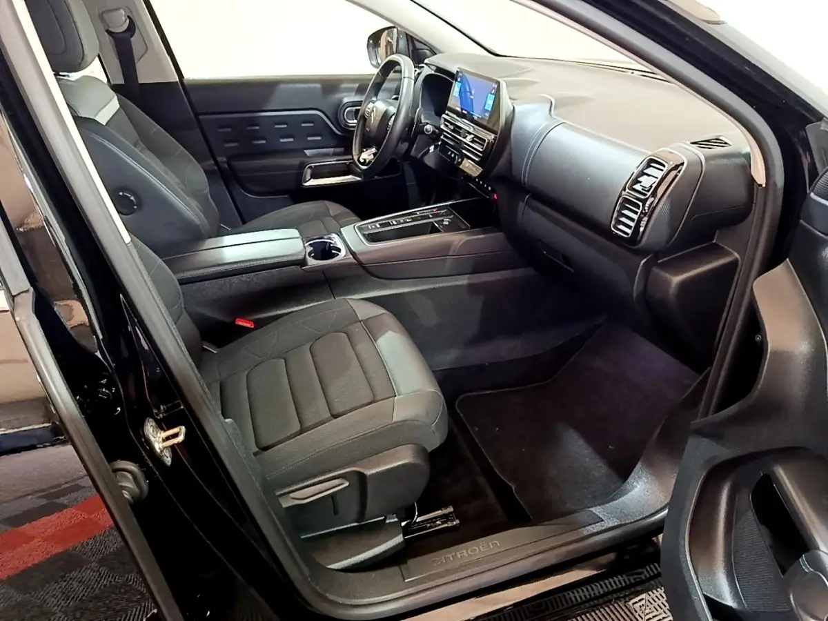 Vue intérieure côté conducteur du Citroën C5 Aircross hybride noir, mettant en valeur le tableau de bord et les sièges avant.