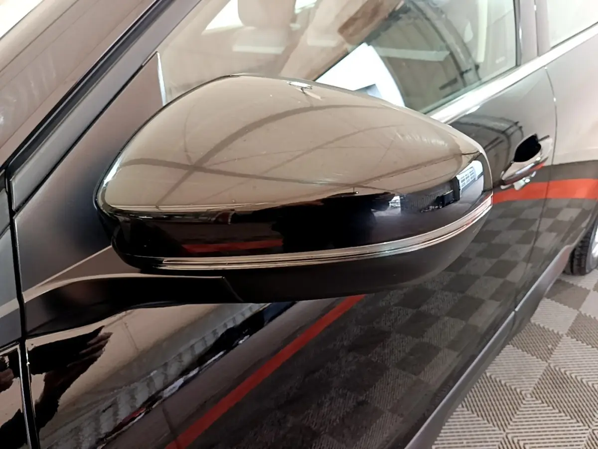Gros plan sur le rétroviseur droit noir brillant du Citroën C5 Aircross hybride rechargeable 2022, avec reflet et porte visible.