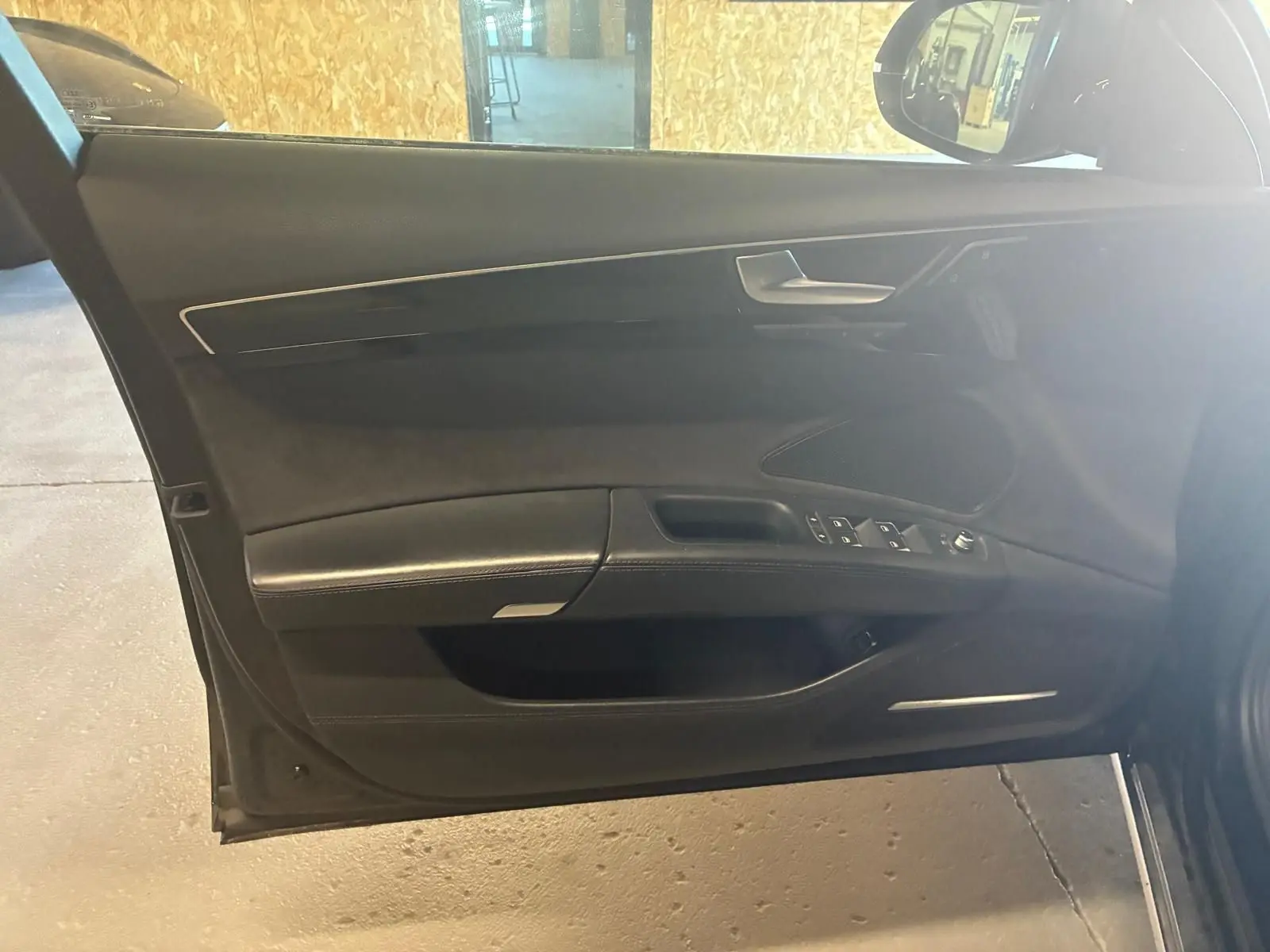 Vue intérieure de la porte avant gauche noire d'une Audi A8 2016, avec commandes de vitres et garniture cuir.