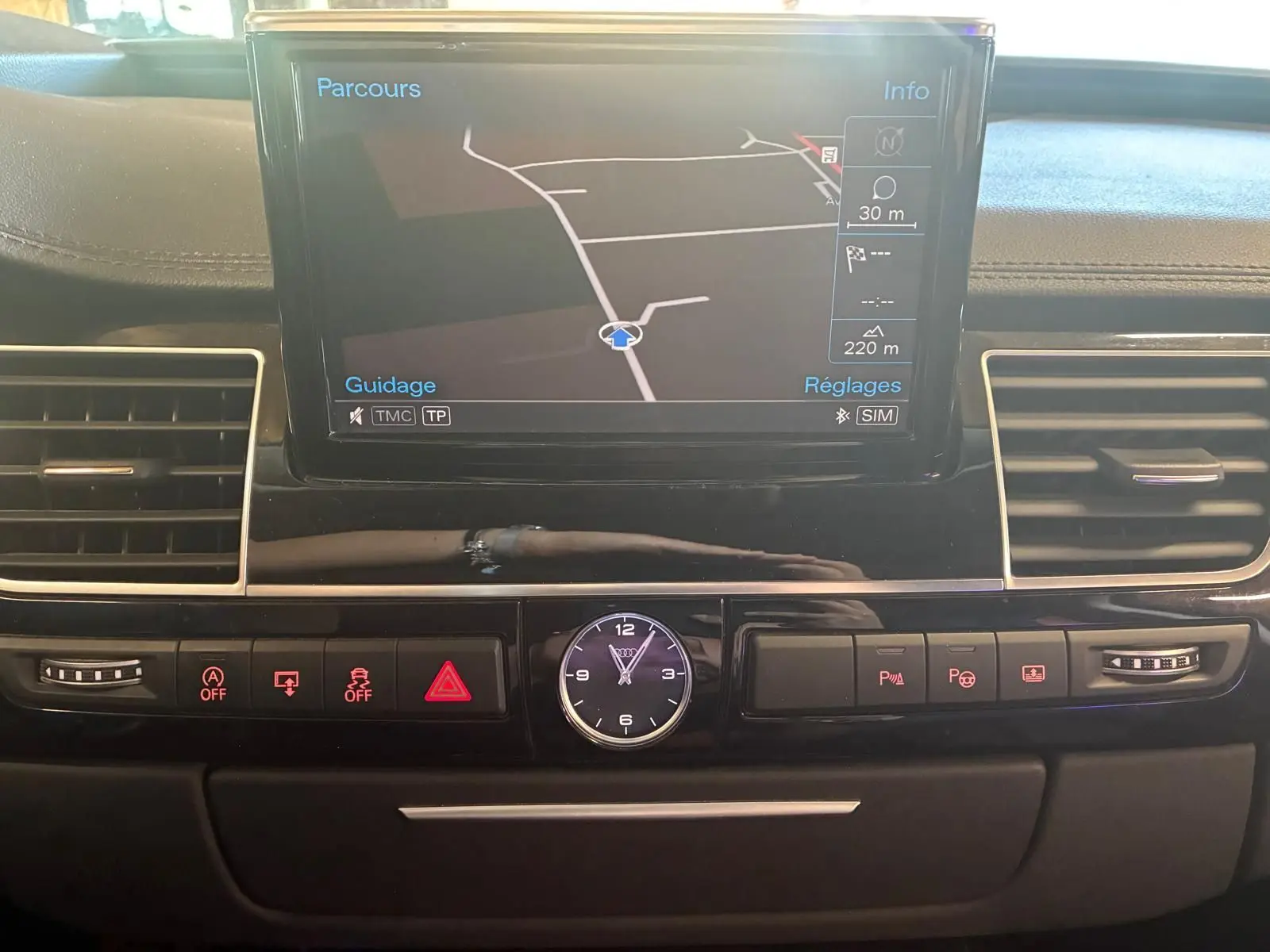 Vue rapprochée du tableau de bord noir de l'Audi A8 2016 avec écran GPS et horloge analogique centrale.