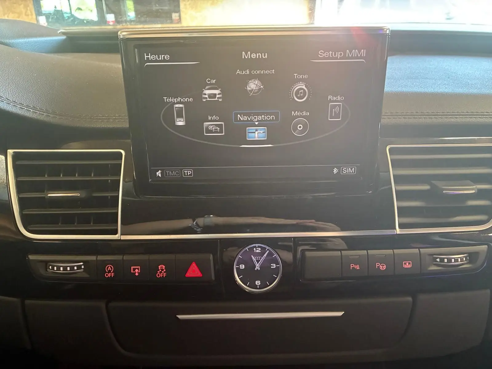 Vue intérieure centrée sur l’écran de navigation et la console noire de l’Audi A8 3.0 TDI 2016 avec horloge analogique.