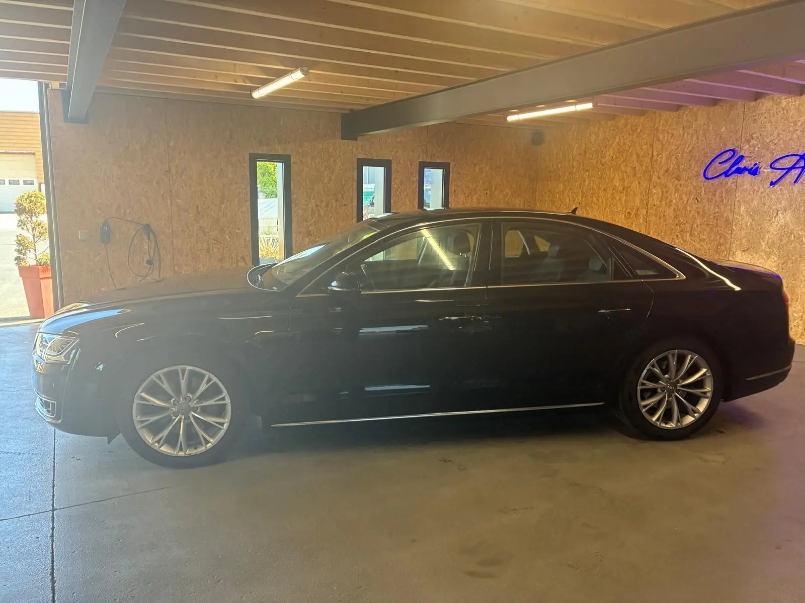 Audi A8 3.0 TDI noire vue de profil côté gauche, stationnée en intérieur avec jantes alliage distinctives.