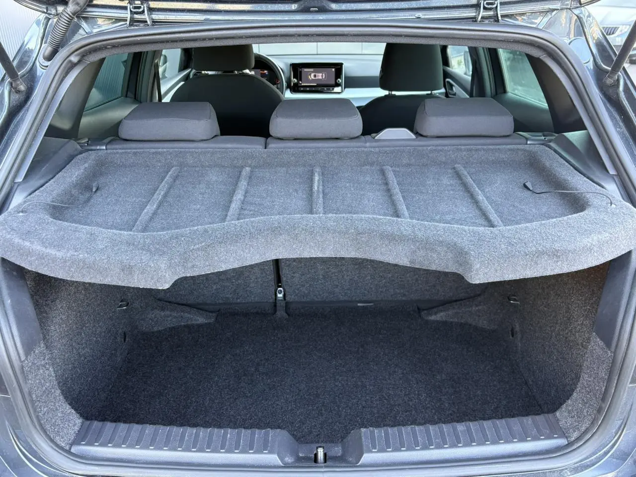 Coffre ouvert d’une SEAT Ibiza gris magnétique, vue arrière montrant l’espace de chargement et l’intérieur avec écran tactile.