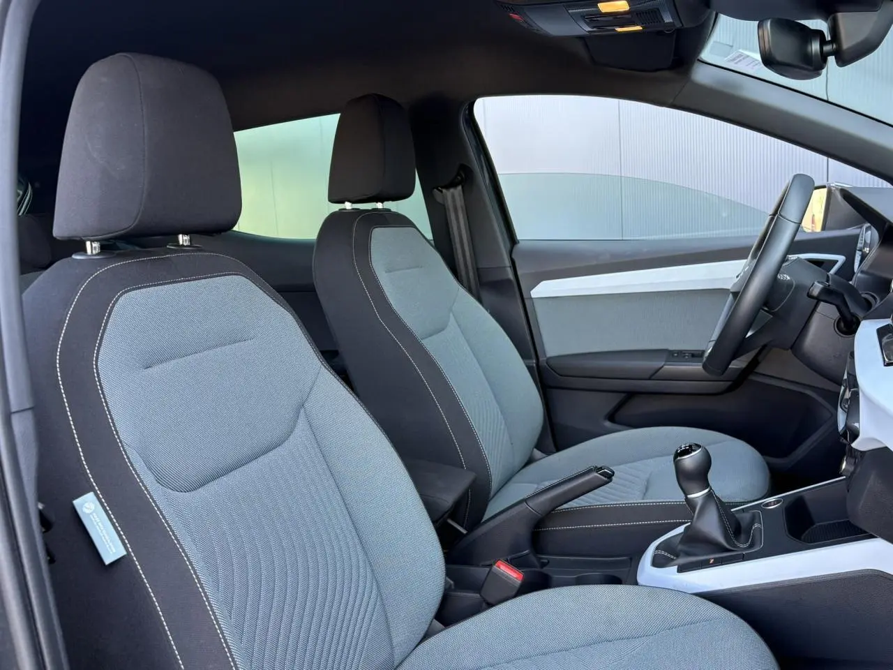 Vue intérieure côté droit montrant les sièges gris clair avec surpiqûres blanches et la console centrale d'une SEAT Ibiza 2025.