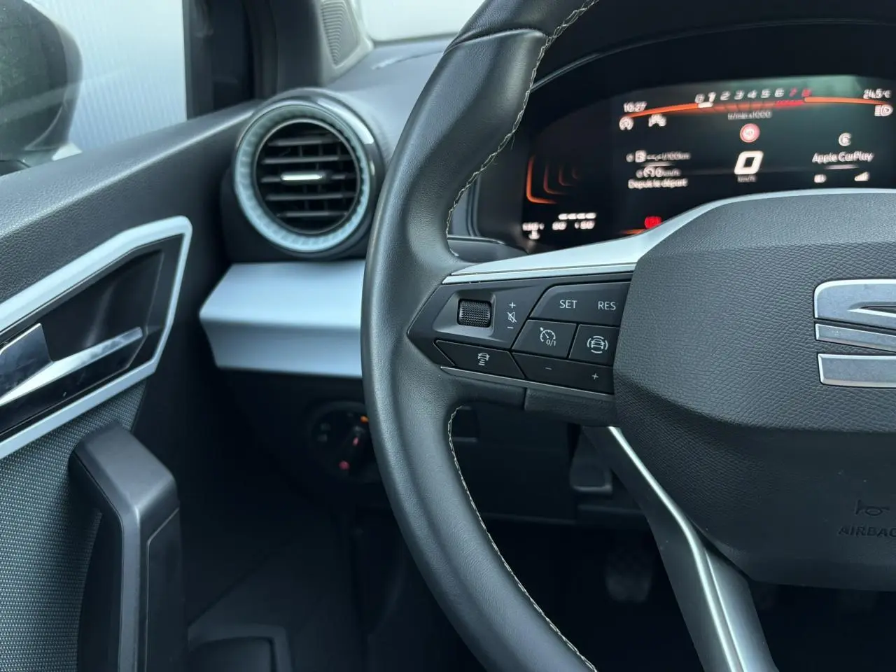 Vue rapprochée du volant cuir noir et du tableau de bord digital de la SEAT Ibiza TSI 115 Xcellence 2025 en gris Magnétique.