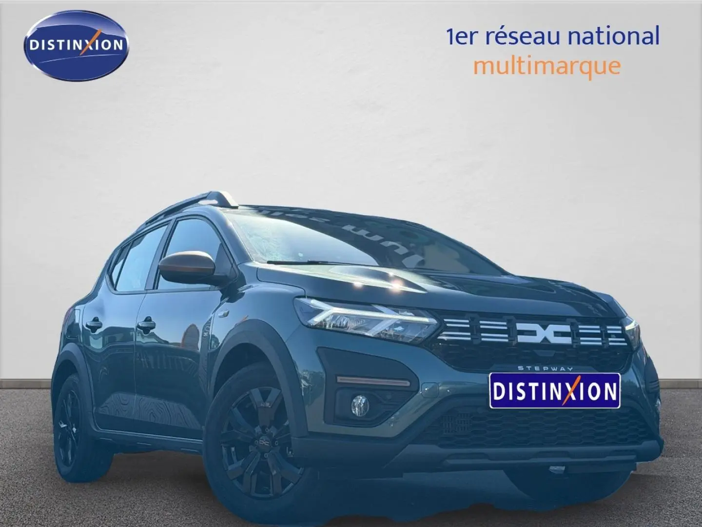 Vue 3/4 avant d'une Dacia Sandero Stepway 2025 vert cèdre métallisé avec jantes noires et barres de toit.