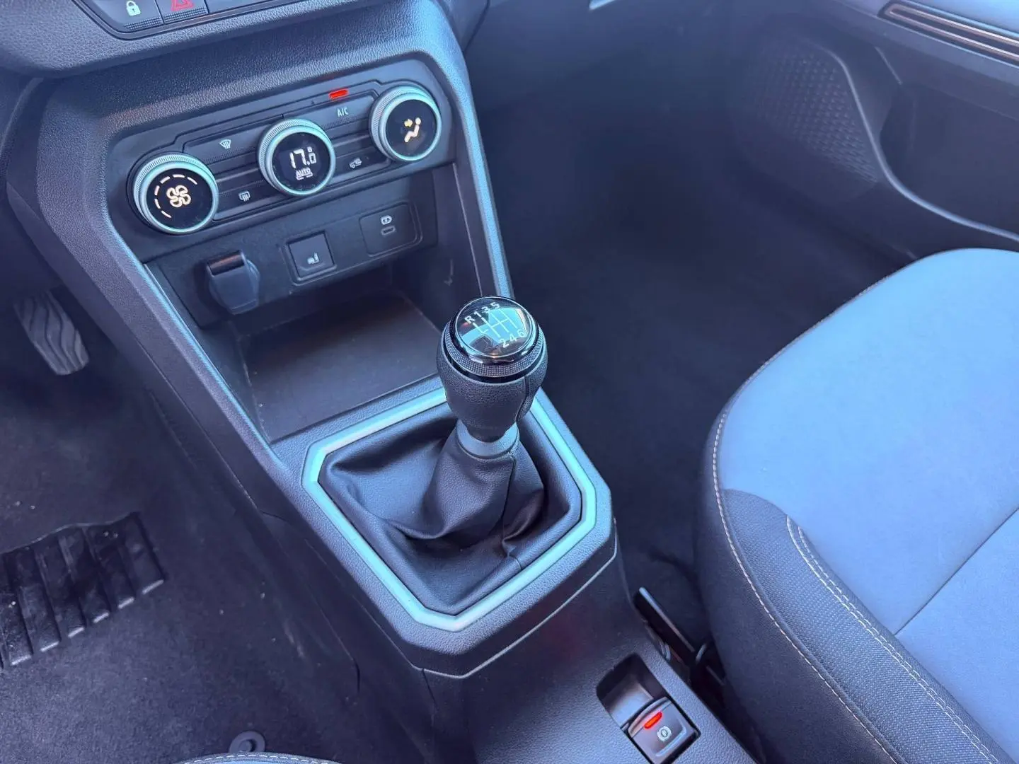 Gros plan sur la console centrale d'une Dacia Sandero 2025, levier de vitesses manuel et commandes climatisation visibles.