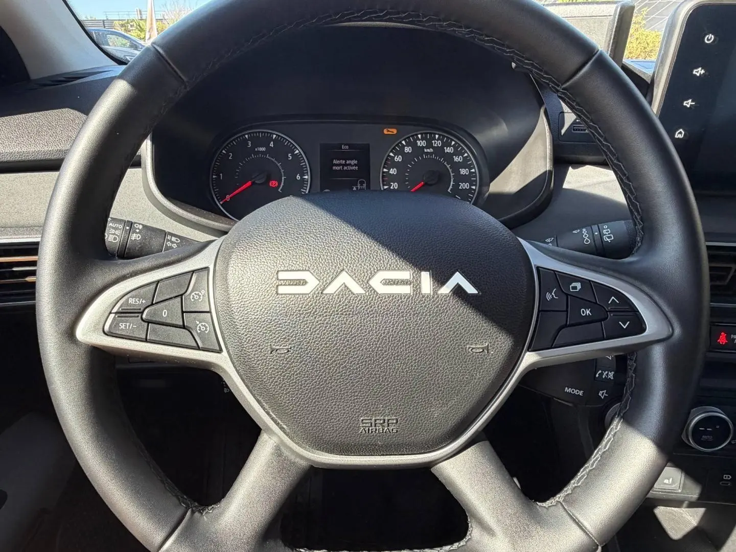 Vue rapprochée du volant noir de la Dacia Sandero 2025 avec commandes intégrées et tableau de bord visible.