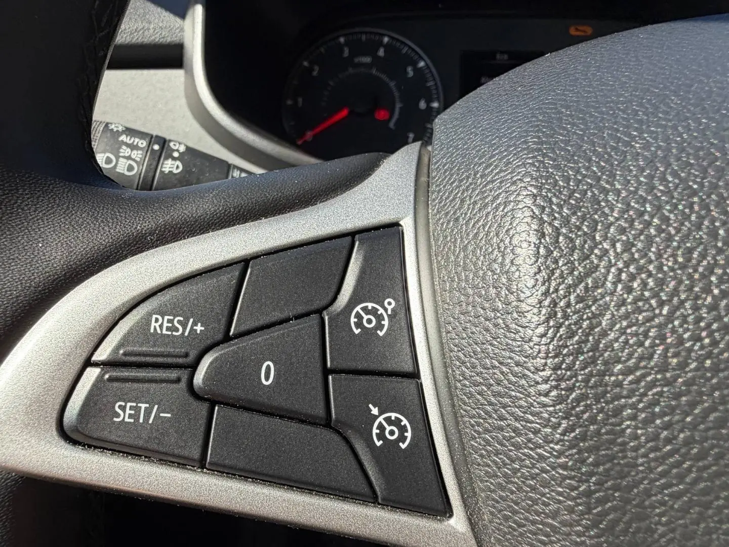Gros plan sur les commandes du régulateur de vitesse au volant d’une Dacia Sandero 2025, intérieur noir.