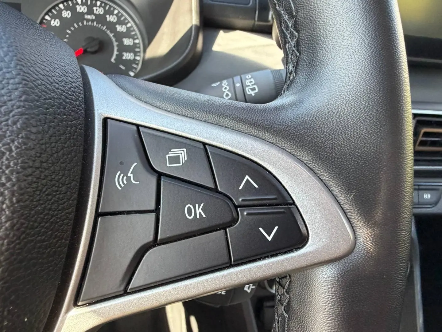 Gros plan sur les commandes multifonctions noires et argent du volant de la Dacia Sandero 2025, intérieur noir.