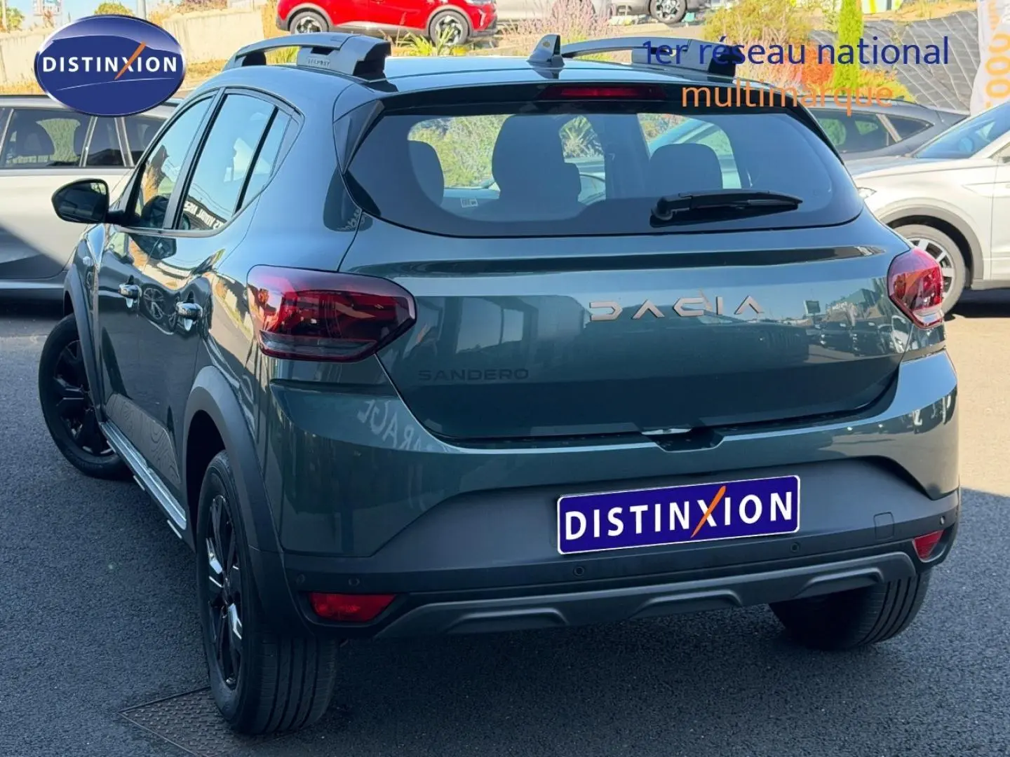Vue 3/4 arrière d'une Dacia Sandero Stepway 2025 vert cèdre métallisé avec jantes noires et barres de toit.